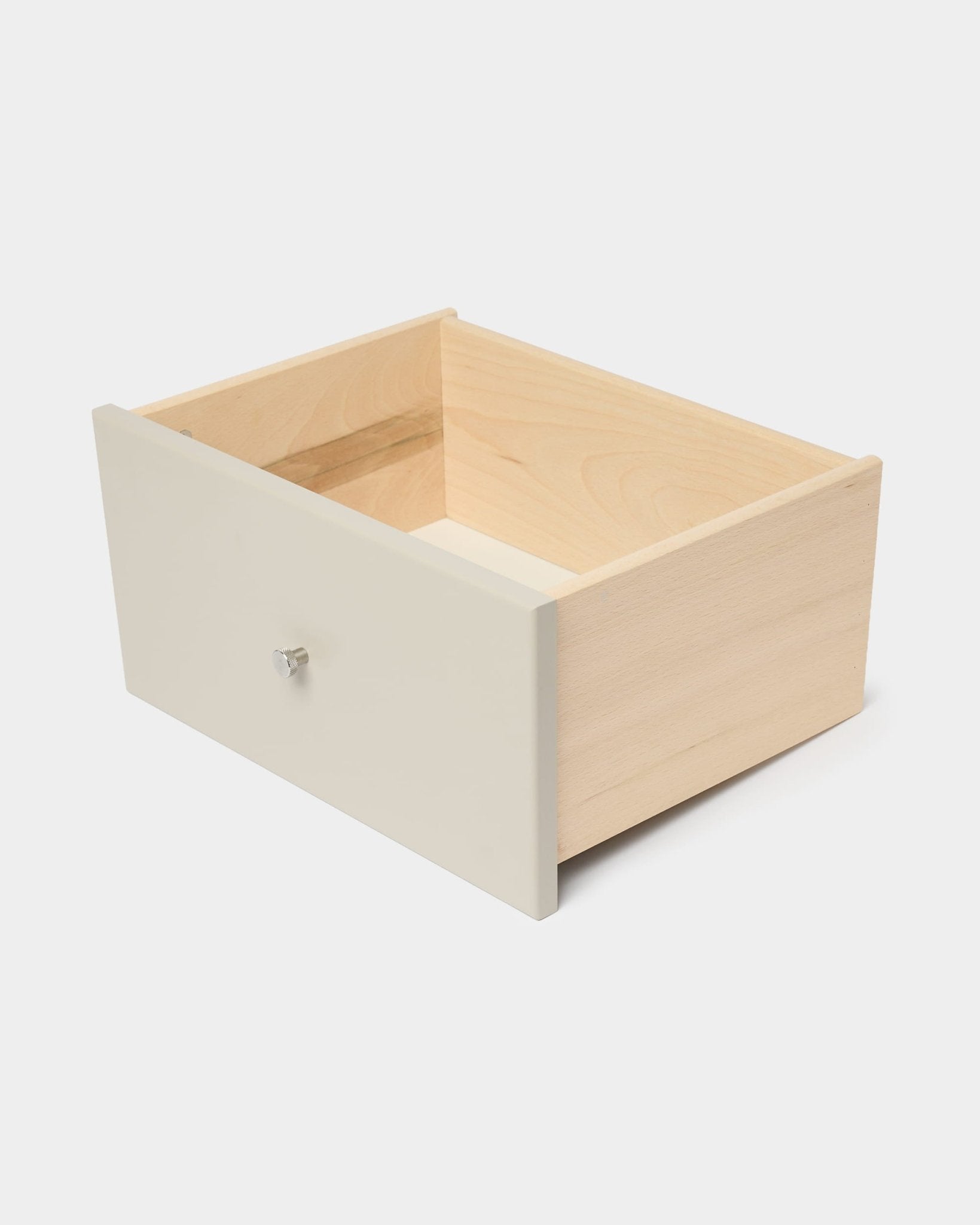 WoodUpp Arka-boekenkast met lade in beige, met een wit frontpaneel en een witte knop, ontworpen voor gesloten opbergruimte, afgebeeld tegen een effen witte achtergrond.